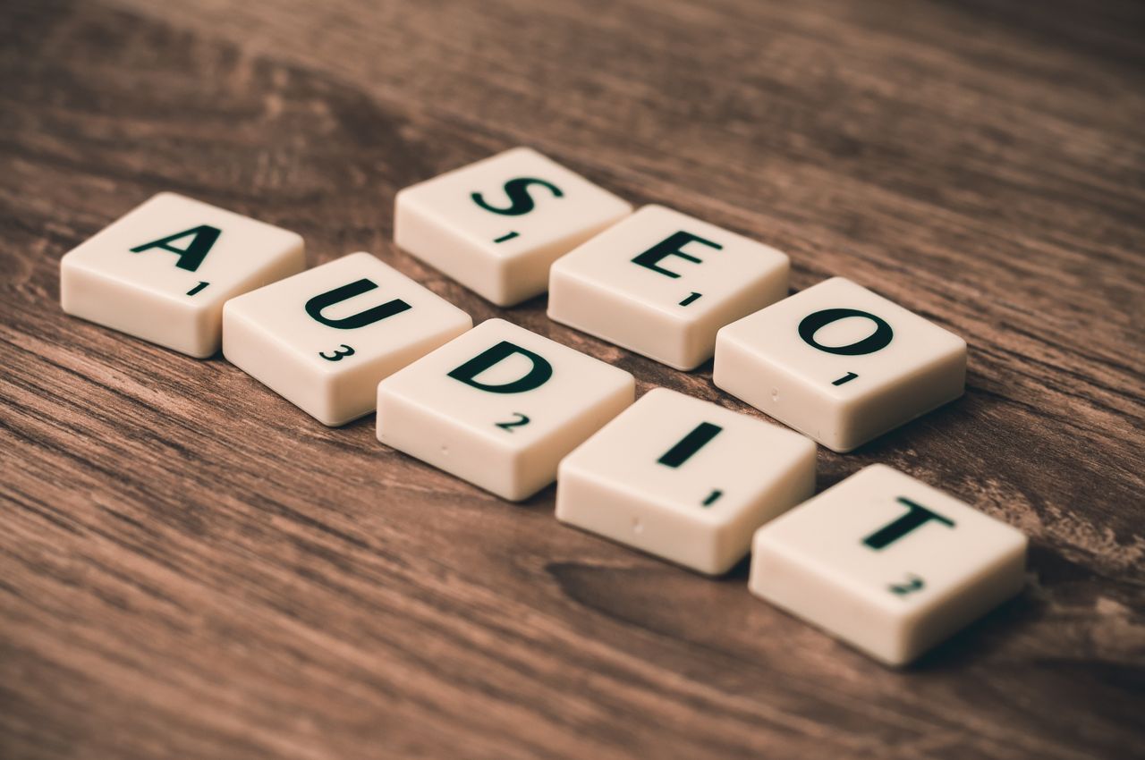 our-story Scrabble tiles spelling SEO Audit on wooden surface, symbolizing digital marketing strategies.